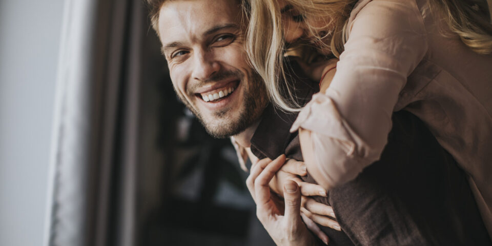 Young man carrying young woman on his back and having fun